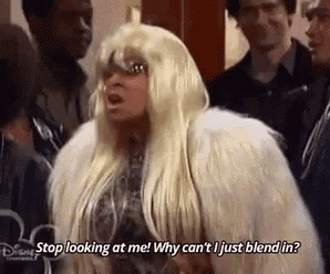 a woman in a wig and fur coat is talking to a group of people and asking why can 't i just blend in