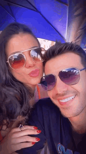 a man and a woman wearing sunglasses are posing for a picture together .