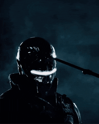 a man wearing a futuristic helmet holds a spear in front of his face