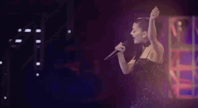 a woman is singing into a microphone in a dark room .