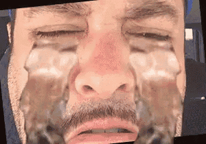 a close up of a man 's face with his eyes closed and a beard .