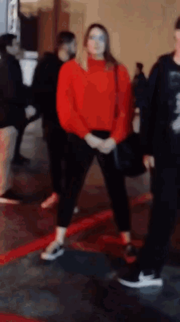 a woman in a red sweater is standing in a crowd