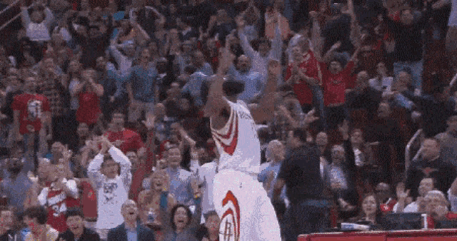 a basketball player is jumping in the air while a crowd watches