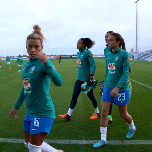 a group of female soccer players are walking on the field