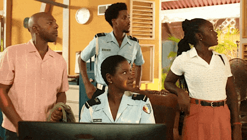a man in a pink shirt stands next to two police officers and a woman in a white shirt stands next to a computer