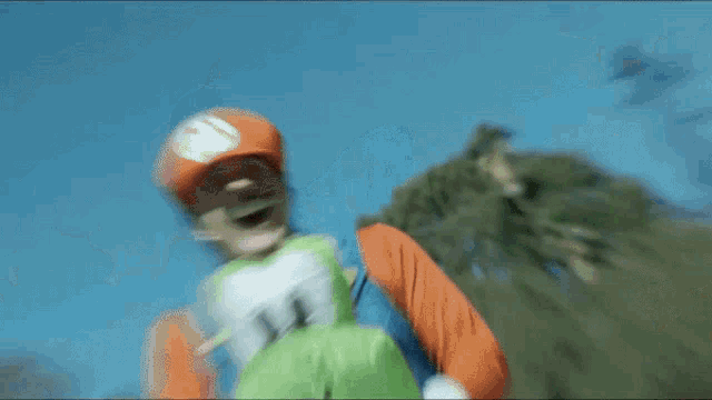 a man in a mario costume is holding a stuffed yoshi and giving a thumbs up