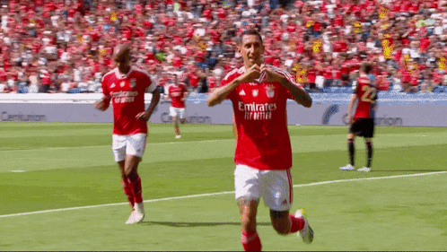 a soccer player wearing a red emirates fly better jersey runs on the field