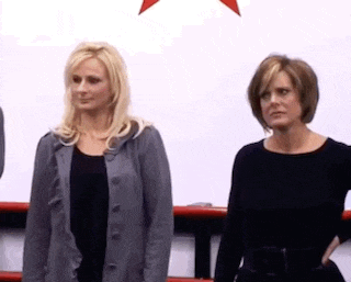 two women are standing next to each other in front of a white background .