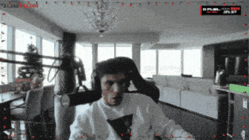 a man wearing headphones is sitting in front of a microphone in a living room with a christmas tree in the background