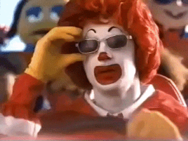 a clown wearing sunglasses and a red wig