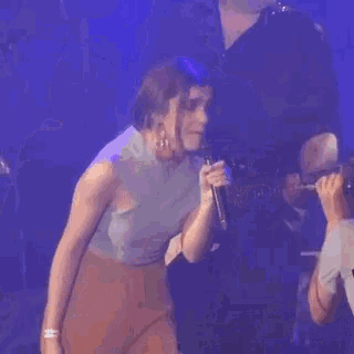 a woman singing into a microphone while standing on a stage