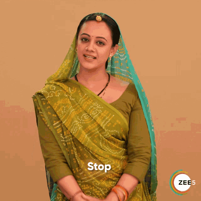 a woman in a green saree is making a stop gesture with her hands