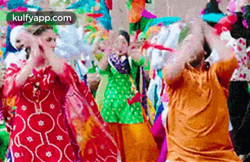 a group of people are dancing in a crowd of people in colorful clothes .