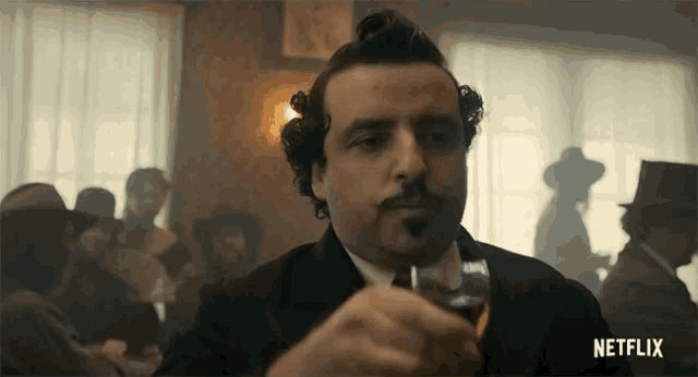 a man with a mustache is holding a glass of whiskey in front of a netflix sign