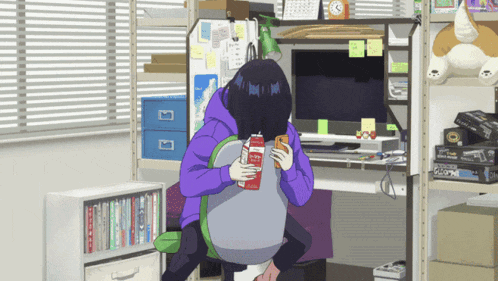 a girl in a purple sweatshirt is sitting at a desk