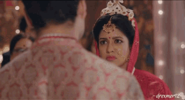 a bride and groom are standing next to each other in front of a crowd of people at a wedding ceremony .