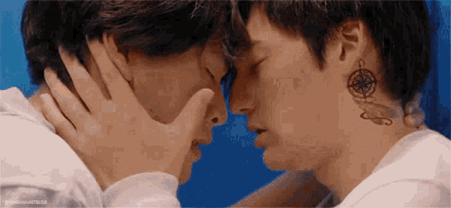 a couple of men are kissing each other on the forehead .