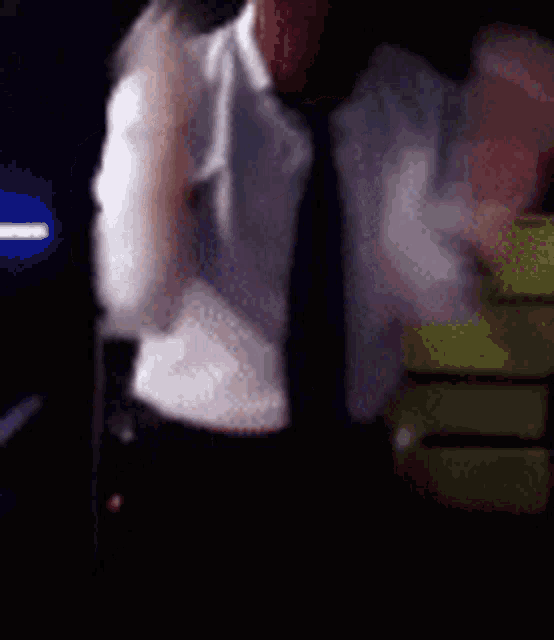 a man in a white shirt and black tie is standing in a dark room .
