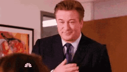 a man in a suit and tie is talking to a woman in a room .