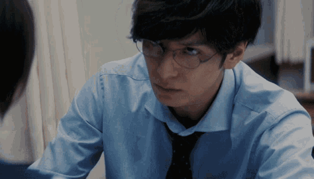 a man wearing glasses and a tie looks at another man