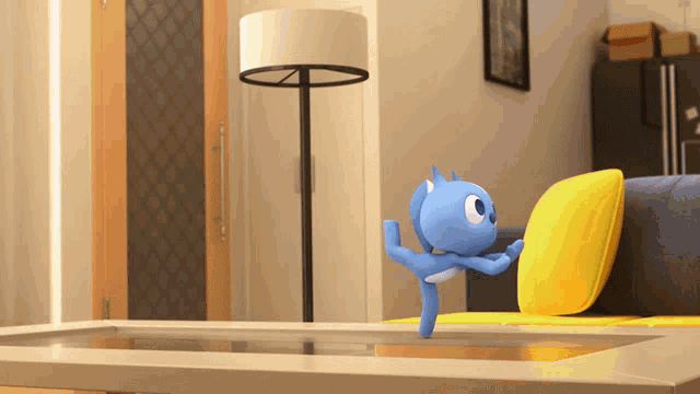 a blue cartoon character is standing on a table next to a yellow pillow