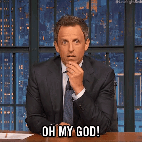 a man in a suit and tie is sitting at a desk and says oh my god