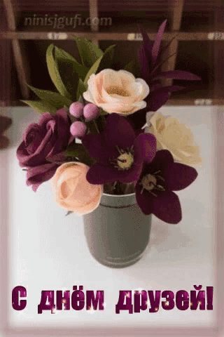 a bouquet of flowers in a vase on a table with a greeting in russian