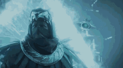 a man in a hooded cloak is standing in a dark room with a blue light coming out of his eyes .