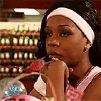 a woman wearing a white headband is sitting in front of a bottle rack