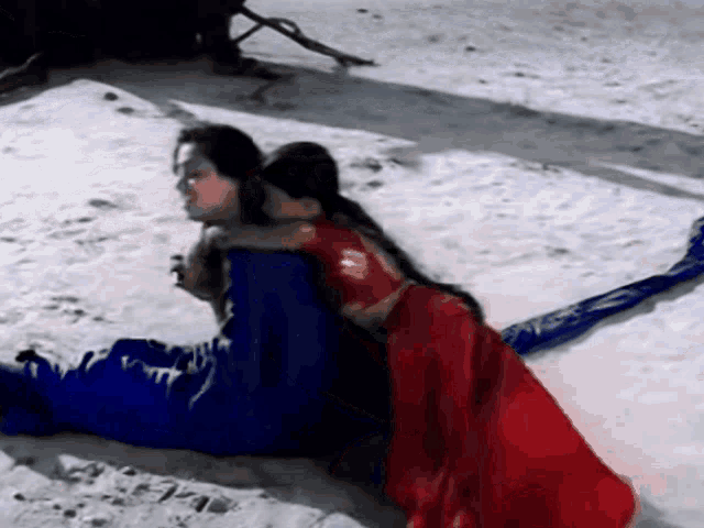 a woman in a red and blue dress is hugging another woman in a blue and red dress