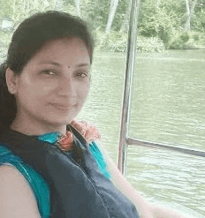 a woman is sitting on a boat in the water and wearing a life jacket .