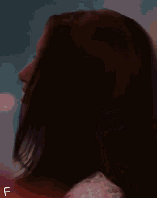 a woman 's hair is blowing in the wind and the letter f is visible in the corner