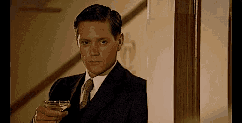 a man in a suit is holding a glass of wine