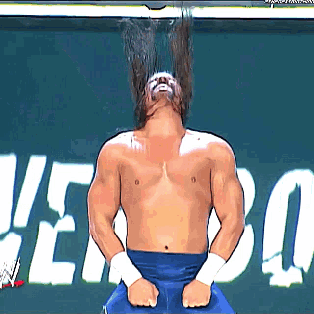 a shirtless wrestler is standing in front of a sign that says ' verbo '