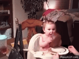 a baby is sitting in a high chair eating food from a plate .