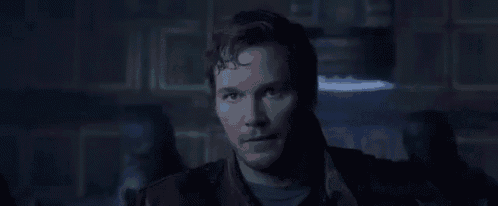 a man with horns on his head and blue eyes is standing in front of a window .