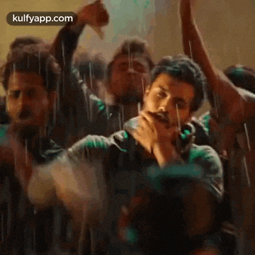 a man is dancing in the rain with a crowd of people behind him .