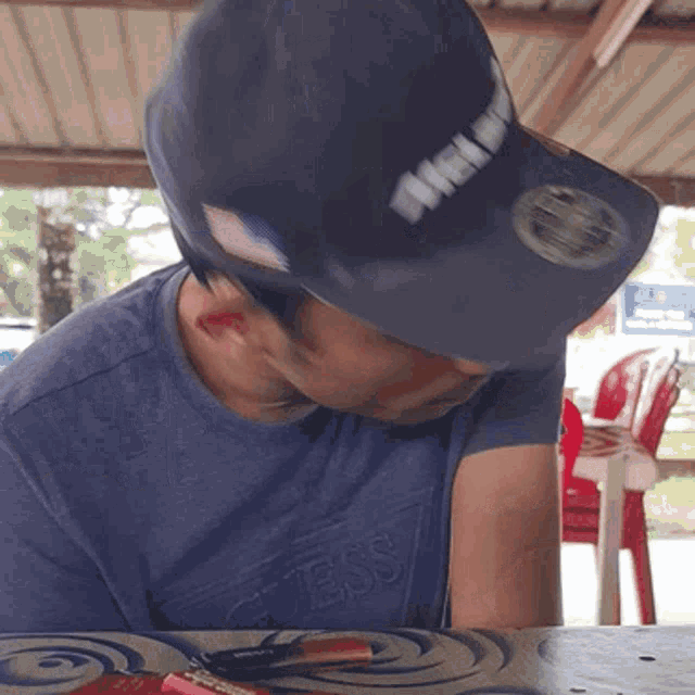 a man wearing a blue shirt that says guess is sitting at a table