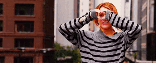 a woman wearing a striped sweater is looking through binoculars