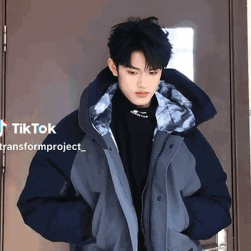 a man in a blue jacket is standing in front of a door with tiktok transformproject written in the corner