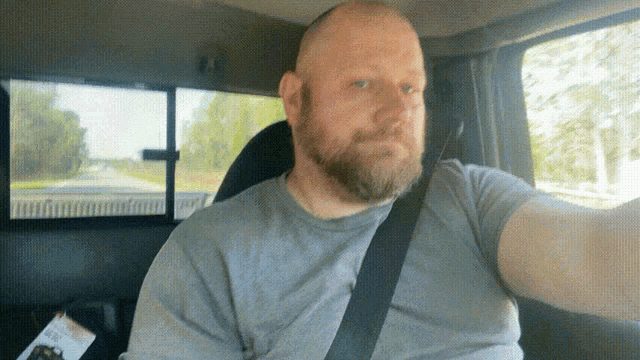 a man with a beard is taking a selfie in the back seat of a car