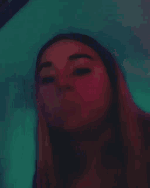 a close up of a woman 's face with a pink background and a red light behind her .