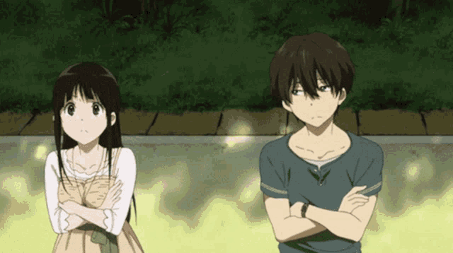 a boy and a girl with their arms crossed standing next to each other
