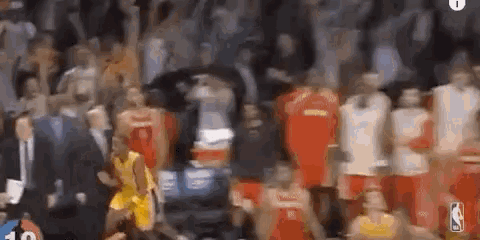 a blurry picture of a basketball game being played in front of a crowd of people .