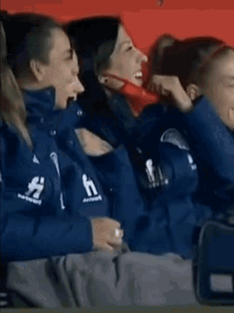 a group of people are sitting in a stadium watching a game and one of them is wearing a mask .