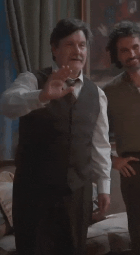 a man wearing a vest and tie is standing in a room