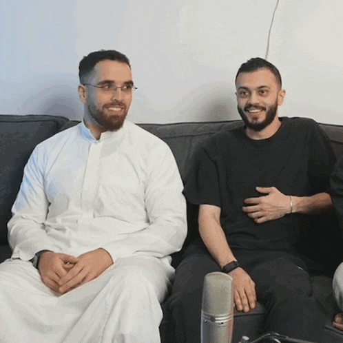 two men sit next to each other on a couch