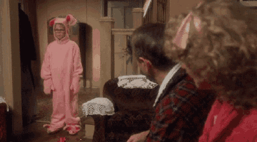 a little girl in a pink bunny costume is standing in a living room with a man and woman .