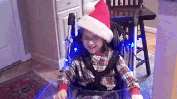 a young girl in a wheelchair wearing a santa hat