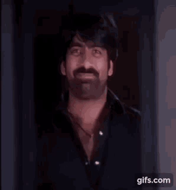 a man with a mustache is smiling while standing in a doorway .